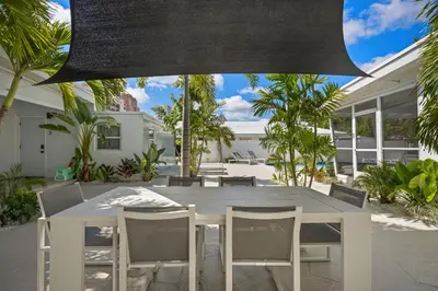 a white dining table and chairs in a yard at The Sandbar Walk To Beach Comfy Beds Firepit Pool in Fort Lauderdale