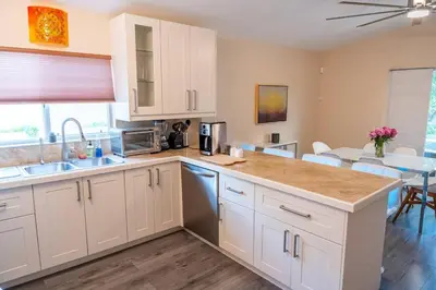 a kitchen with white cabinets and a dining room at 5 min to airport and 15 min to beach! in Fort Lauderdale