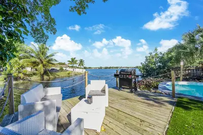 a dock with chairs and a boat on the water at Dior Lake Front Villa With Infinity Pool in Miami Gardens