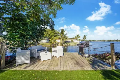 a wooden dock with chairs and a grill on the water at Dior Lake Front Villa With Infinity Pool in Miami Gardens