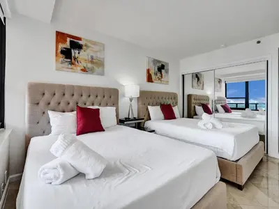 two beds in a bedroom with white and red pillows at Beach Resort condo 921 in Miami Beach