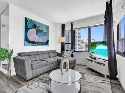 a living room with a couch and a tv at Full ocean view Huge private terrace 1002 in Miami Beach