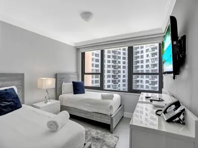 a white room with two beds and a tv at Amazing 3BD Ocean View Condo Beach Service 715 in Miami Beach