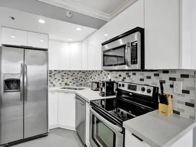 a kitchen with white cabinets and a stainless steel refrigerator at Amazing 3BD Ocean View Condo Beach Service 715 in Miami Beach