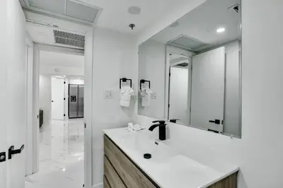 a white bathroom with a sink and a mirror at Cozy Ocean View Condo Beach Service and Pool 808 in Miami Beach