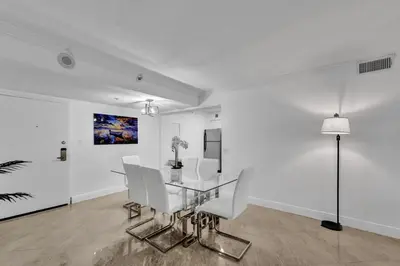a dining room with a glass table and white chairs at Cozy Ocean View Condo Beach Service 1015 in Miami Beach