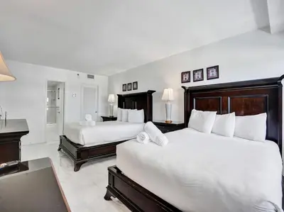 a bedroom with two beds with white sheets and a piano at Lovely Ocean View Condo Beach Service 704 in Miami Beach