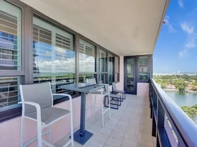 a balcony with tables and chairs and a view of the water at Luxury Beachfront Condo Beach Service 1418 in Miami Beach
