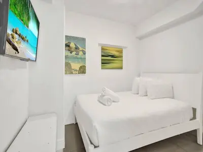a white bedroom with a white bed and paintings on the wall at Spacious Ocean View Condo Beach Service 509 in Miami Beach