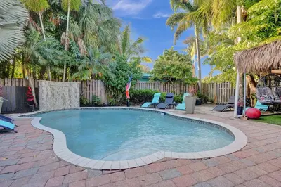 a swimming pool in a yard with chairs and trees at Kiki Grand Suite - Men's Clothing optional Guest Houses in Fort Lauderdale