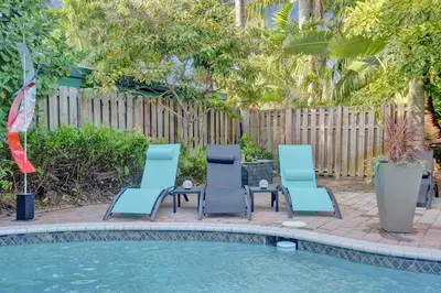three chairs and a table next to a swimming pool at Kiki 2 - Men's Clothing optional Guest Houses in Fort Lauderdale