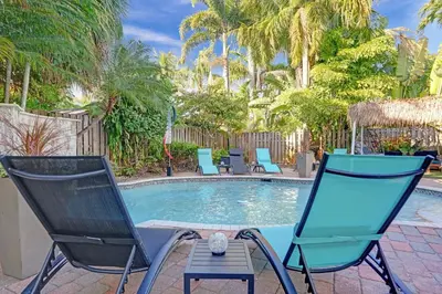 two chairs and a pool with palm trees at Kiki 2 - Men's Clothing optional Guest Houses in Fort Lauderdale