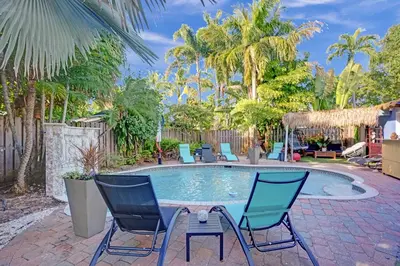 a pool with chairs and a table in a yard at Kiki 3 - Men's Clothing optional Guest Houses in Fort Lauderdale