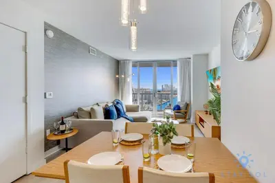 a dining room and living room with a large clock on the wall at Infinite View Balcony Gym Amaizing Pool in Hallandale Beach