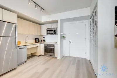 a kitchen with white cabinets and a stainless steel refrigerator at Infinite View Balcony Gym Amaizing Pool in Hallandale Beach