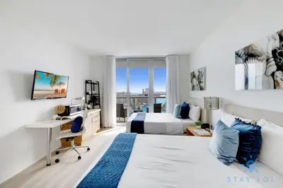 a bedroom with a bed and a desk and a bed at Infinite View Balcony Gym Amaizing Pool in Hallandale Beach