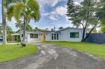 a white house with a palm tree and a driveway at Chic Florida Retreat with Pool, Patio and Gas Grill! in Fort Lauderdale