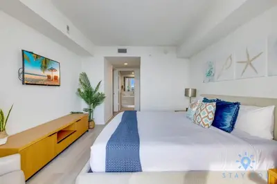 a white bedroom with a large bed and a desk at Amaizing Pool Infinity View w Balcony Gym in Hallandale Beach