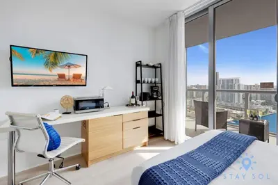 a bedroom with a desk and a bed and a window at Upper studio w Balcony Pool Gym Near Beach in Hallandale Beach