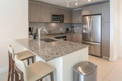 a kitchen with a counter with a sink and a refrigerator at Stunning Apartment in Downtown Doral in Miami