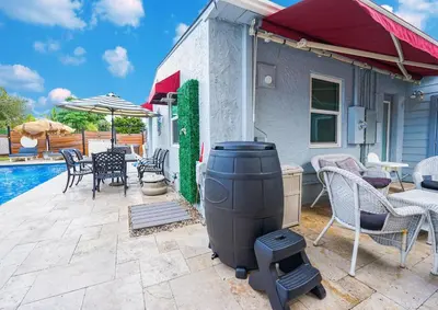 a grill on a patio next to a pool at Palms Retreat! Giant Heated Pool-HotTub-FirePit-5Min2Beach-Pets-EV Chgr in Fort Lauderdale