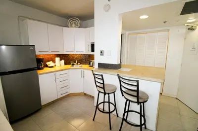 a kitchen with two bar stools and a refrigerator at Castle 1120 Bayview Studio, Beach access, Pool, Tennis, Free parking in Miami Beach