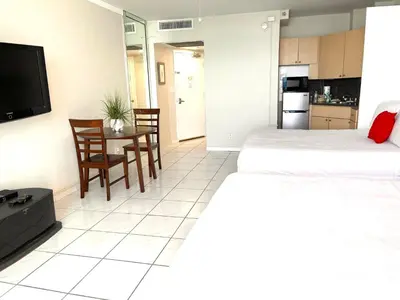 a room with two beds and a table and a kitchen at Castle 1527 Studio Balcony Direct Beach Access, Pool, Tennis, Free Parking in Miami Beach