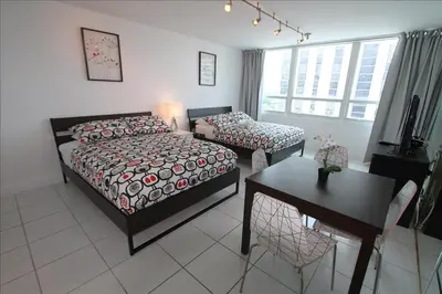 a bedroom with two beds and a table and a desk at Castle 515 Studio BayView Direct Beach Access, Pool, Tennis, Free Parking in Miami Beach
