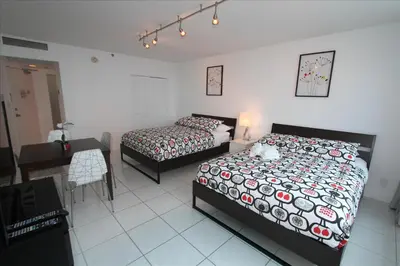 a bedroom with two beds and a table and a desk at Castle 515 Studio BayView Direct Beach Access, Pool, Tennis, Free Parking in Miami Beach
