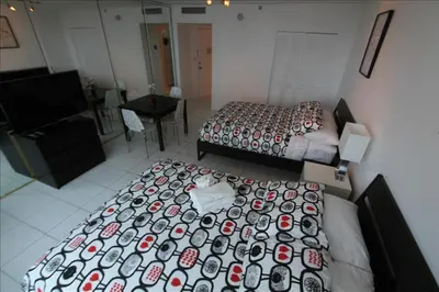 a bedroom with two beds and a desk and a television at Castle 515 Studio BayView Direct Beach Access, Pool, Tennis, Free Parking in Miami Beach