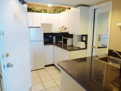 a kitchen with white cabinets and a white refrigerator at Castle 727 Studio with balcony and Ocean view, Pool, Tennis, Beach Access, Free Parking in Miami Beach