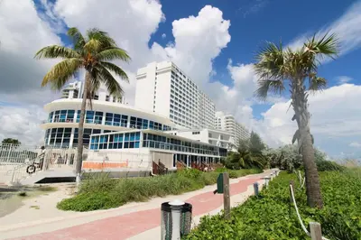 a large building with palm trees in front of it at Castle M4 Beachfront Balcony Loft, FREE Parking, Pool, Tennis, Beach Access in Miami Beach