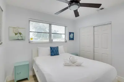 a bedroom with a white bed with a ceiling fan at Luxe Miami Home Outdoor Kitchen, Gas Grill! in Miami Gardens