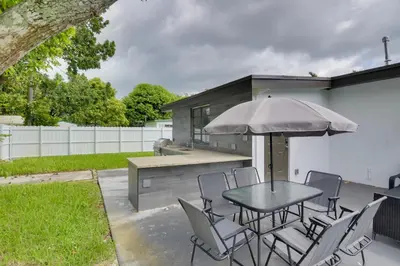 a patio with a table and chairs and an umbrella at Luxe Miami Home Outdoor Kitchen, Gas Grill! in Miami Gardens