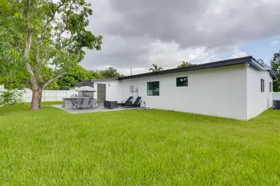 a white house with a large yard at Luxe Miami Home Outdoor Kitchen, Gas Grill! in Miami Gardens
