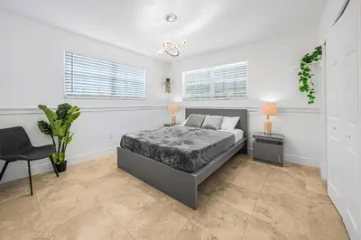 a white bedroom with a bed and a chair at New Tropical Oasis Retreat in Miami in Miami