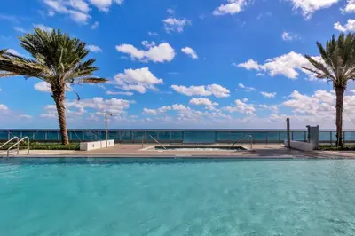 a swimming pool with palm trees and the ocean at Dharma Home Suites Miami Beach at Monte Carlo in Miami Beach