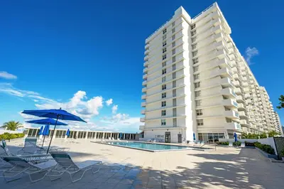 a large white building with chairs and an umbrella at Pavilion Residences on the Beach in Miami Beach
