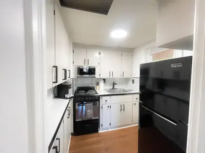 a kitchen with white cabinets and a black refrigerator at New Miami Boutique, by Calle Ocho and South Beach! in Miami