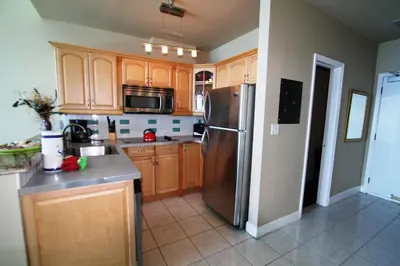 a kitchen with wooden cabinets and a stainless steel refrigerator at Castle Ph2 Balcony Oceanfront Condo, Beach Access, Pool, Tennis, Free Parking in Miami Beach