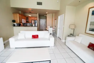 a living room with two white couches and a kitchen at Castle Ph2 Balcony Oceanfront Condo, Beach Access, Pool, Tennis, Free Parking in Miami Beach