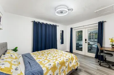 a bedroom with a bed and a desk and blue curtains at Sunrise Getaway in Sunrise