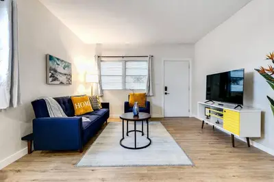 a living room with a blue couch and a tv at Stylish 2BR central Fast Wi fi virg2 in Miami
