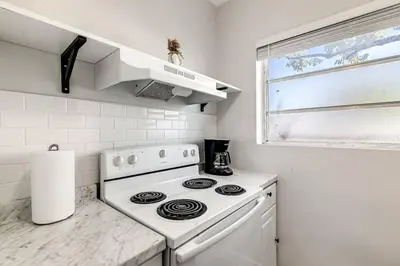 a white kitchen with a stove and a window at Mia Springs 2BR wi-fi Virg 3 in Miami