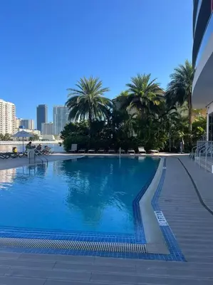 a large swimming pool with palm trees in a city at Exclusive Miami Beach Stay , Views & Modern Comfort -A in Hallandale Beach