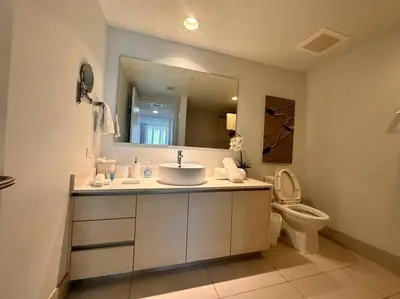 a bathroom with a sink and a toilet and a mirror at High-End Miami Condo, Ocean Views & Kitchen -A in Hallandale Beach
