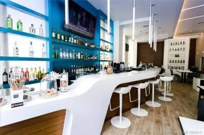 a bar with a white counter and bar stools at Oceanfront Elegance, Full Kitchen & Miami Beach Charm -A in Hallandale Beach