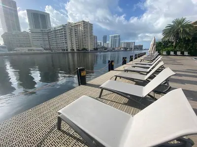 a row of white lounge chairs next to a body of water at Chic Miami Beach Stay, Comfort, Style & Sea Views -A in Hallandale Beach