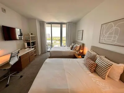 a large hotel room with a bed and a desk at Disfruta como en Miami, hermoso estudio para 4 in BeachWalk in Hallandale Beach
