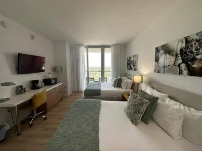 a bedroom with two beds and a desk with a computer at Make Yourself at Home , Inviting Studio in Miami in Hallandale Beach